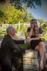 a man is kneeling on a stone wall to propose to a woman